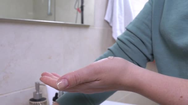 Женщина наносит маслянистый косметический продукт на запястье для проверки реакции на аллергию ее кожи в ванной комнате, закрыть. Дневные ритуалы красоты и ухода за кожей — стоковое видео