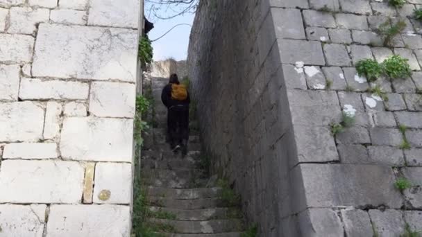 Mann mit Rucksack steigt Steintreppe zwischen hohen Mauern hinauf — Stockvideo
