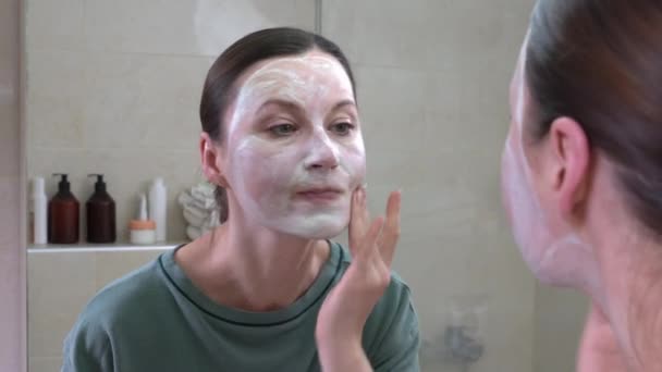 中年黑发女人在脸上涂保湿面膜 — 图库视频影像