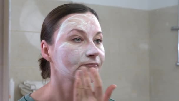 Volwassen vrouw past natuurlijke masker op gezicht kijken in spiegel — Stockvideo
