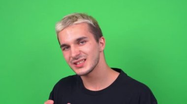 Duygusal genç adam Chromakey 'de kameraya poz vererek şarkı söylüyor.