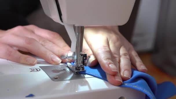 Adapte las reparaciones o hace ropa nueva usando la máquina de coser profesional, primer plano, vista superior. Persona puntadas borde costura en el borde de la tela y lo comprueba — Vídeo de stock