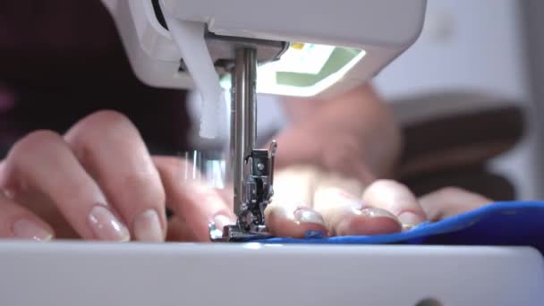Sömmerska syr nya kläder med hjälp av professionell symaskin, närbild, framifrån. Personsömmar kantsöm med tråd på tygkanten — Stockvideo