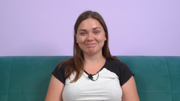 Young smiling woman is being interviewed online for new position in office. Female blogger is streaming live for her vlog with entertaining or educational content with humor, front view — Vídeos de Stock