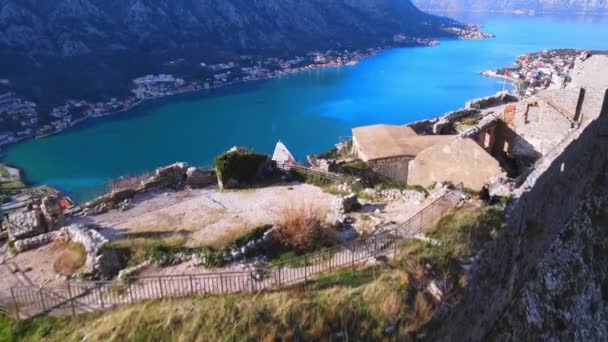 Skytte med en drönare flyger över medeltida österrikiska fästning i riktning mot otroligt vackra Kotorbukten och gamla stan vid foten av bergen, Montenegro, ovanifrån — Stockvideo