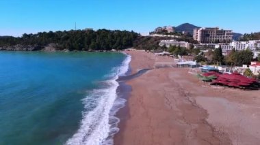 Turkuaz deniz dalgaları parktaki boş kumsalda dalgalanır.