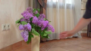 Adam yerden harika leylak çiçekli vazoyu alır.