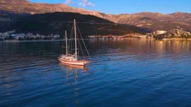 Zevk ya da balıkçı teknesi körfezde denize açılır, kameralı insansız hava aracı etrafta uçar ve kuşbakışı çekim yapar. Karadağ 'ın dağlarının eteğindeki eski Avrupa kenti Budva