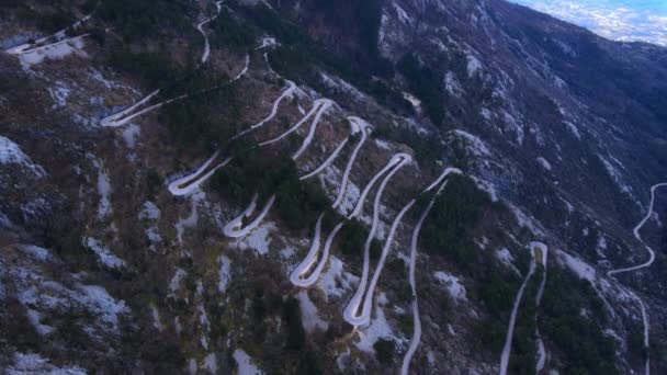 Top panoramisch uitzicht op gevaarlijke serpentine weg van Kotor naar Lovcen berg, drone schieten. Helling is bedekt met schaars bos en vegetatie, waardoor je kale rots kunt zien — Stockvideo