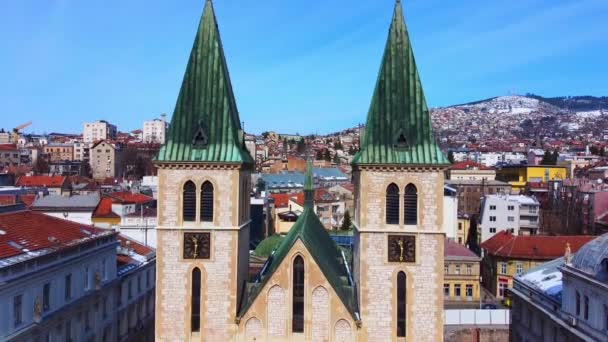 Drönare med kamera ner till marken, visar utsikt över fasaden av det heliga hjärtat katedralen från tak till grund, främre vy, som ligger på torget, Bosnien och Hercegovina — Stockvideo