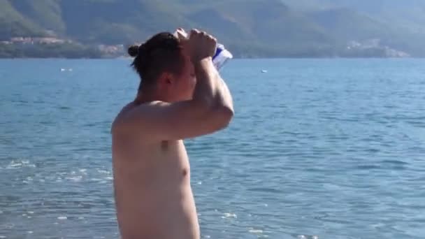 Killen sätter på sig simglasögon stående i havsvatten och dyker — Stockvideo