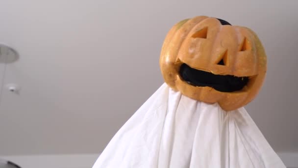 Person i handgjord spökdräkt med pumpa jack-o-lantern med läskigt ansikte i stället för huvud vill busa vänner och skrämma dem eller gör konstiga kusliga prestanda på Halloween fest — Stockvideo