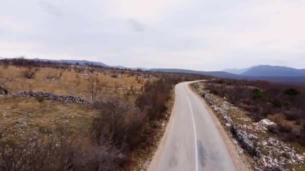 Aszfaltozott út fut a hegyvidéken között lejtők száraz fű — Stock videók