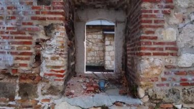 Kameralı insansız hava aracı Saraybosna 'daki eski Taslihan kervanının harabelerinden oluşan duvarın harap olmuş penceresinden uçarak uzaklaşıyor. Eski Avrupa kasabasının manzaralarını keşfet. Seyahat günlüğü