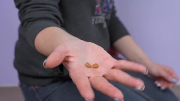 Blanke persoon toont verschillende pellets van gedroogde voeders voor gezelschapsdieren of behandelen houden ze in open palm, dan verbergt ze in de hand, close-up. Reclame voor diervoeders. — Stockvideo