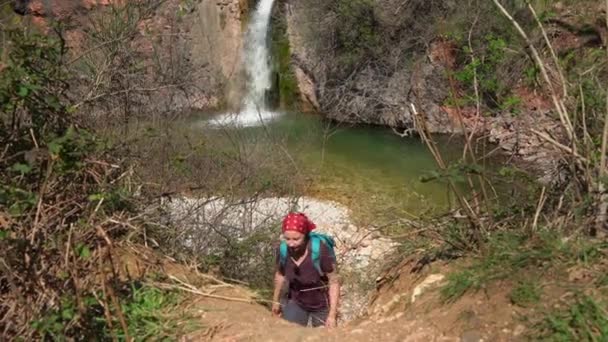 Joven turista con bandana roja sube camino de la colina — Vídeos de Stock