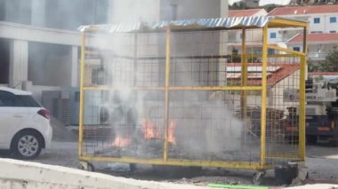 Kağıt yakar ve sigara içer. Ayrı çöp toplama için bariyerli konteynırda meydana gelen bir kaza sonucu. Suç şehrinin sokaklarında vandalizm, ön manzara