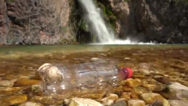 Пластиковая бутылка для отходов на прозрачной озерной воде с волнами — стоковое видео