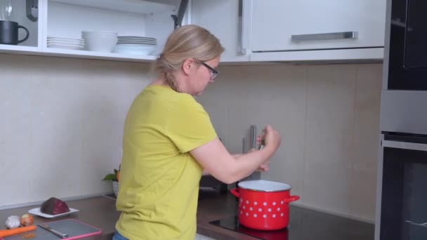 Hemmafrun lagar god mat i köket. Ung blond kvinna gör soppa och lägga kryddor för att förbättra smaken med hjälp av manuella kryddor kvarn — Stockvideo