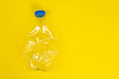 Buruşmuş plastik şişe, sarı arka planda duruyor, üst manzara, kopyalama alanı. Daha fazla atık geri dönüşümü işlemi için çöplerin sınıflandırılması. Çevre kirliliği sorunu