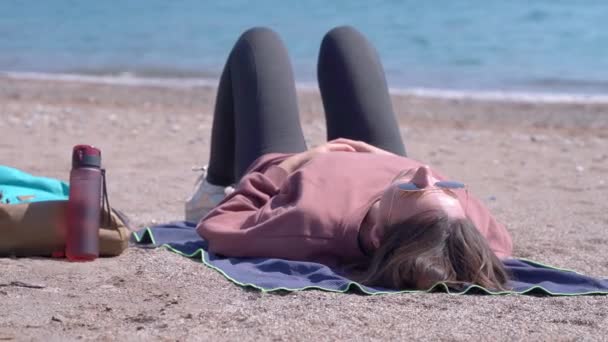 Kobieta z plecakiem i termos leży na piaszczystej plaży w pobliżu morza — Wideo stockowe
