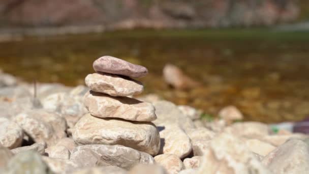 Small brown pebble stones lie in pile on bank against lake — Stock Video