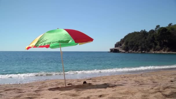 Heller Sonnenschirm am leeren Strand in der Nähe des azurblauen Meeres installiert — Stockvideo