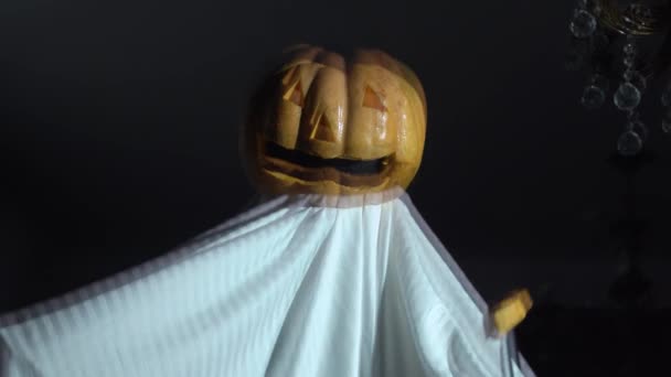 Person makes horror performance at Halloween party. Actor in homemade ghost costume with pumpkin with creepy face instead of head and knife in his hand appears in frame — Stock Video