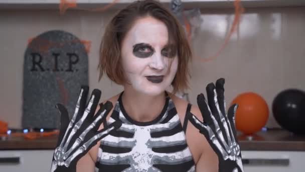 Ung galen kvinna med läskig makeup och skelett kostym pjäser och grimaser vid kameran. Skådespelerska iscensatt föreställning för vänner på Halloween fest — Stockvideo