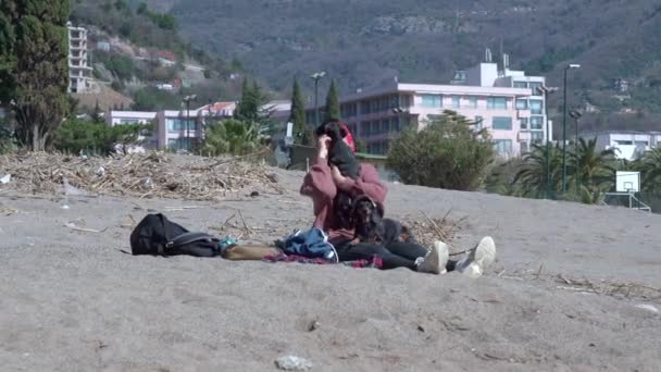 Mujer propietaria abraza pequeño perro Dachshund en la playa de arena por hotel — Vídeos de Stock