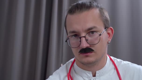 Arzt mit Brille und falschem Schnurrbart nickt neben Vorhang — Stockvideo
