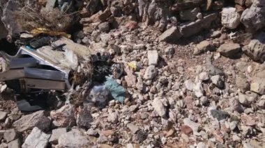 Terk edilmiş arabasıyla kahverengi dağlık bir arazi.