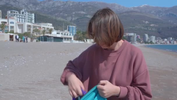 Vrouw met riem trekt rugzak aan om langs het strand weg te lopen — Stockvideo