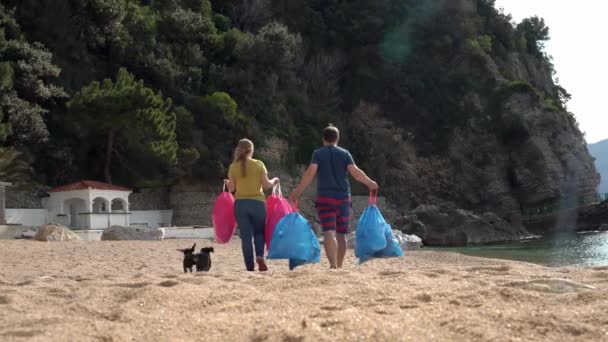 Voluntários com cães carregam sacos com lixo ao longo da praia — Vídeo de Stock