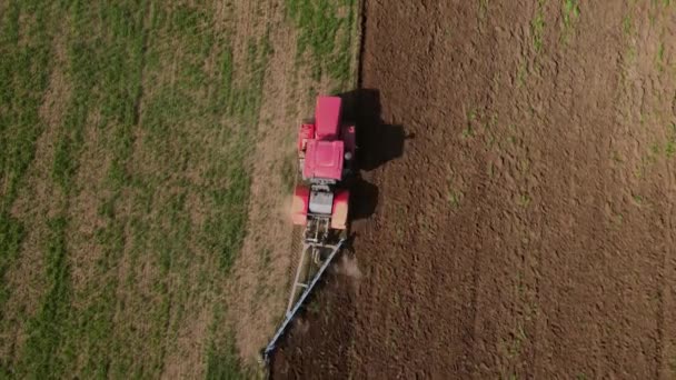 Özel ekipman otlarıyla dolu traktör, yeni mevsimde ekime toprak hazırlamak için toprağı sürdükten sonra tarlayı sürüyor, yukarıdan görüyor, İHA ateşi açıyor. Tarım kavramı — Stok video