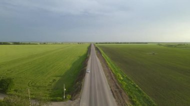 Yeşil tarlalar arasında otomobilli gri asfalt yol