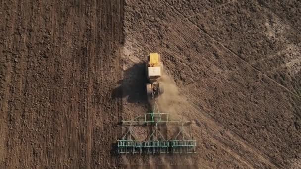 Maquinaria agrícola pesada con gradas afloja el suelo, preparándolo para la siembra de trigo en las zonas rurales, vista superior, tiro con dron desde una altura — Vídeo de stock