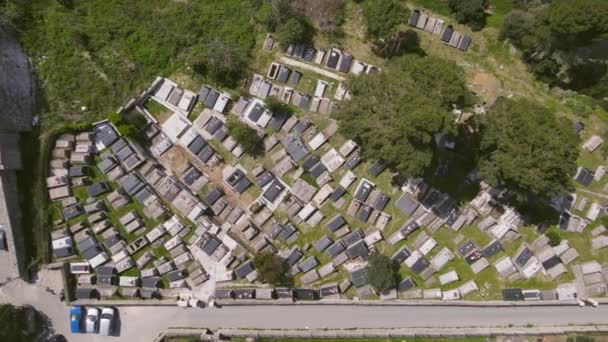 Drone com câmera se move ao longo do cemitério com grandes lápides, e estrada com estacionamento em frente a ele, antiga cidade turística de Ulcinj na costa do Adriático em Montenegro, vista superior — Vídeo de Stock