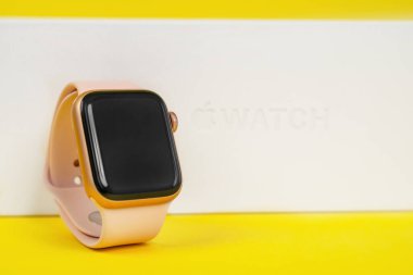 29 Mayıs, Rostov, Rusya: Apple Watch 6 serisi üzerine pembe kauçuk kayış bağlanmış beyaz kutu sarı arka plan, kopyalama alanı. Etkin bir yaşam biçimi için akıllı aygıt