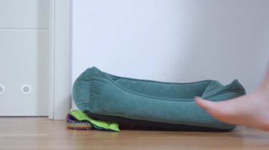 Çıplak ayaklı bir adam yerde boş yeşil bir yastığın yanından geçiyor.