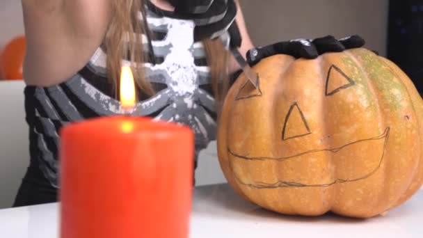 Femme en gants noirs découpe les yeux en citrouille mûre avec couteau le long du contour dessiné pour faire lanterne jack pour décorer appartement pour la fête d'Halloween, fermer — Video