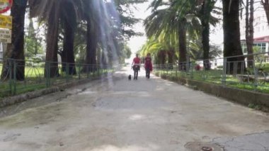 Spor elbiseli kadınlar köpekle birlikte tatil köyü yolunda yürürler.