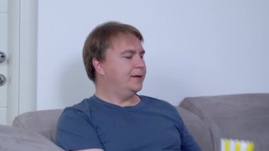 Sağlıksız yaşam tarzını yöneten genç şişman adam mukavva çizgili kovadan son patlamış mısırı ağzına attı. Yemek bittiği için hayal kırıklığına uğradı ve daha fazlasını istiyor.