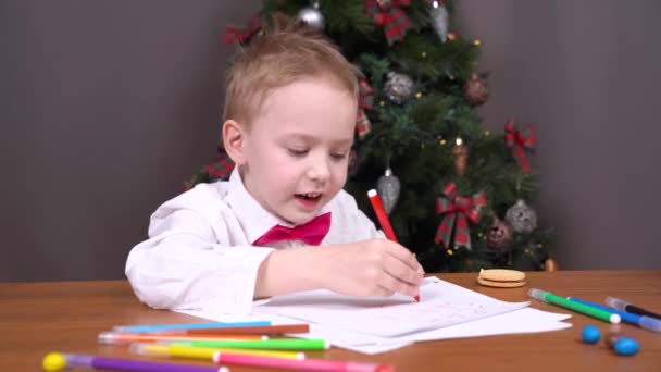 良い男の子は一年中よく振る舞っているので、彼はそれについて彼の両親とクールな贈り物や相談を得るためにサンタに願いを込めて手紙を書くか、または魅力的なクリスマスの物語を伝えます — ストック動画