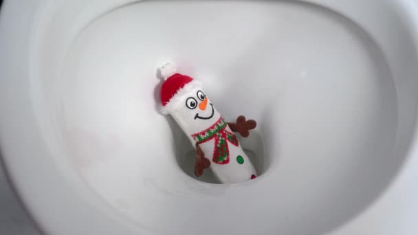 Toy snowman in red hat inside toilet and water runs closeup — Stock Video