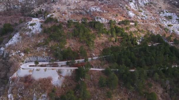 Side panoramisch uitzicht op extreme serpentine weg op helling van de berg bedekt met schaarse vegetatie, Montenegro, drone schieten. Gevaarlijke scherpe bocht — Stockvideo