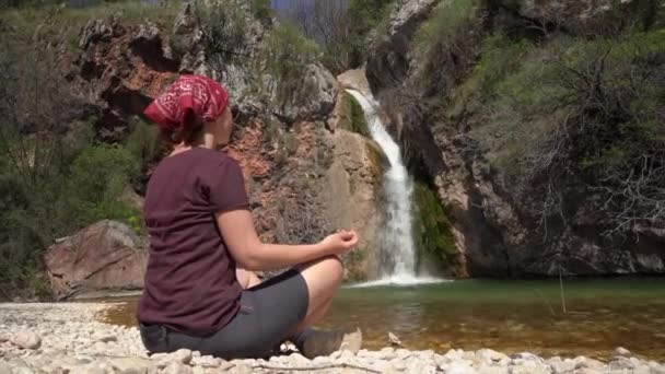 Young woman in red bandana meditates sitting in yoga pose — Stock Video