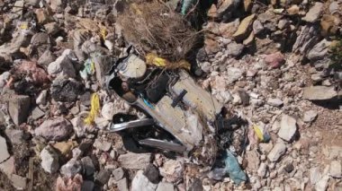 Tamamen kırılmış paslı arabanın kalıntıları kayaların, enkazların ve kuru dalların arasında uzanıyor. Kameralı dron yavaşça eksen etrafında dönüyor. Yıkılmış araç kaza sonucu uçurumdan aşağı uçtu.