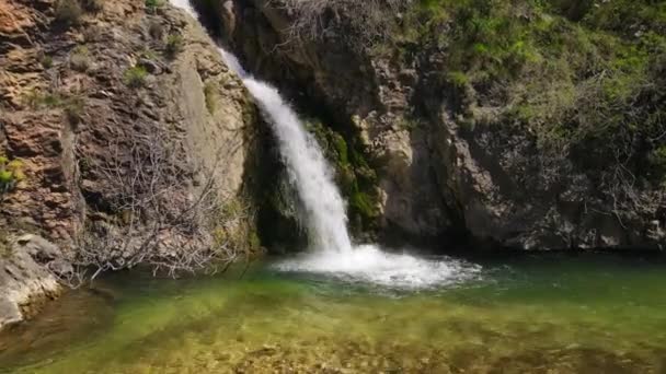 L'eau moussante blanche tombe dans le lac depuis une falaise rocheuse brune — Video