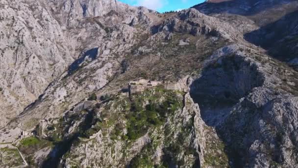 Dron vystřelil z výšky, která se blíží ke staré rakouské zchátralé pevnosti na vrcholu útesu, zálivu Kotor, Černá Hora. Krásný panoramatický výhled na horskou krajinu — Stock video